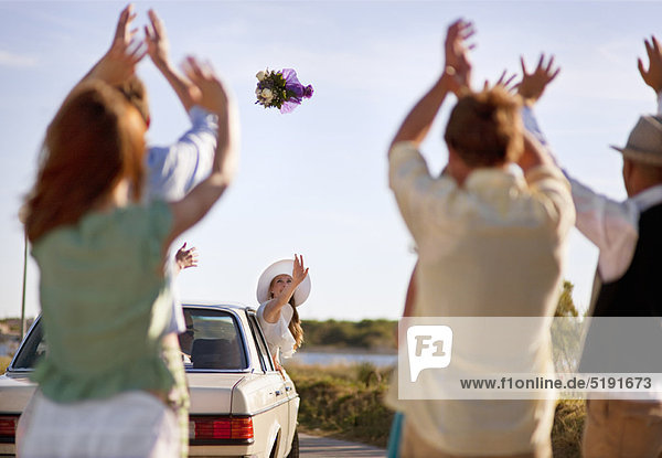 Bride throwing bouquet from car