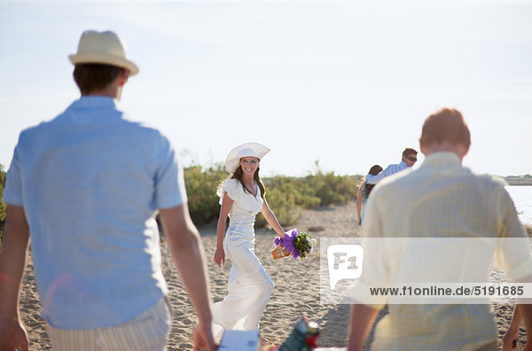 Bride walking with friends on beach