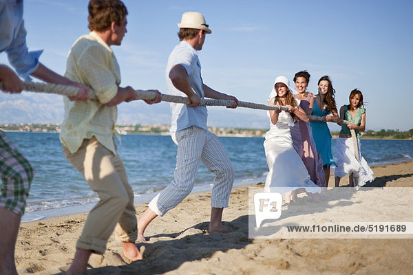Newlyweds and guests playing tug of war