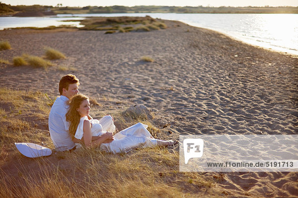 Newlywed couple sitting on beach