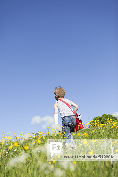 Junge läuft durch ein Blumenfeld