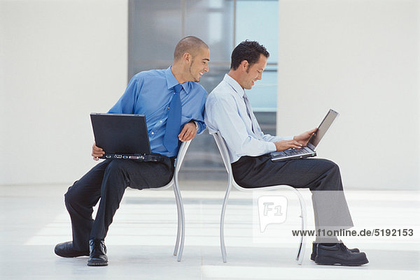 Businessmen working on laptops in office