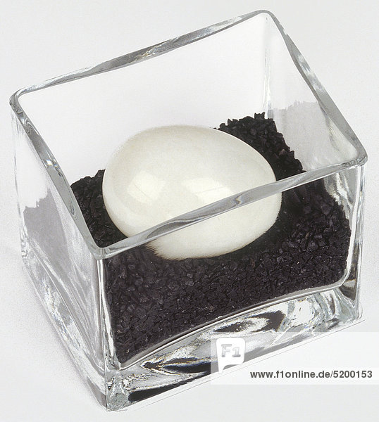 Weißes Stein-Ei in kleinem Glasgefäß