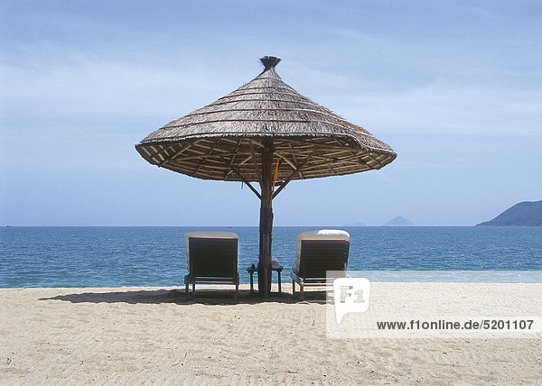 Sonnenschirm aus Schilfrohr  zwei Liegestühle am Strand  Natrang  Vietnam