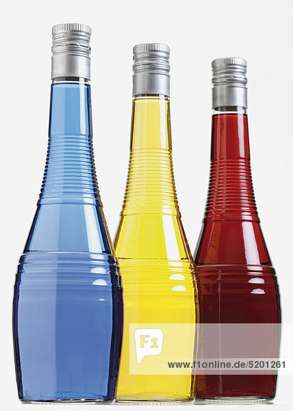 Drei Flaschen mit farbigen Likören