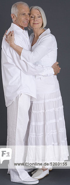 Seniorenpaar  weiß gekleidet  umarmt