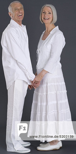 Seniorenpaar  weiß gekleidet  halten Händchen  lachen