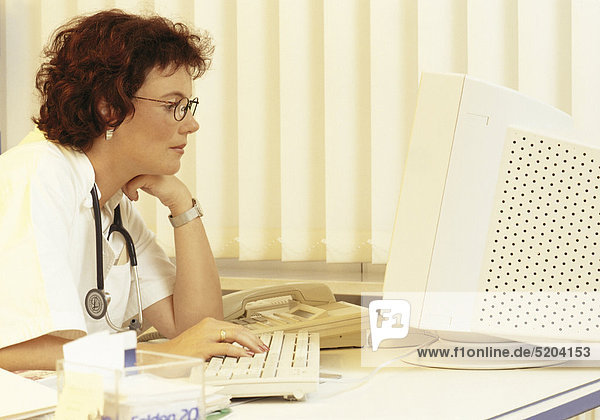 Ärztin am Schreibtisch vor Monitor