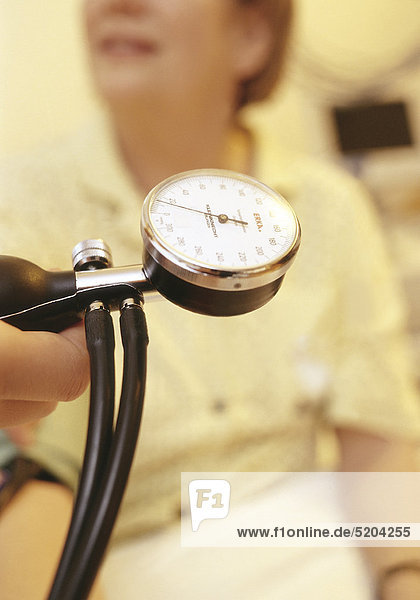 Blutdruckmessgerät  Anzeige  im Hintergrund Patientin