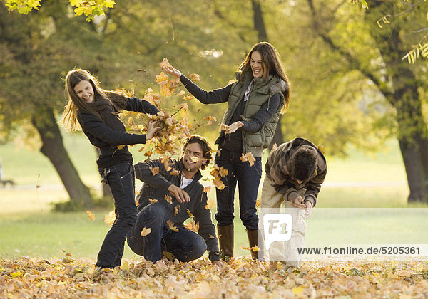 Familie in herbstlichem Park  werfen mit Herbstlaub