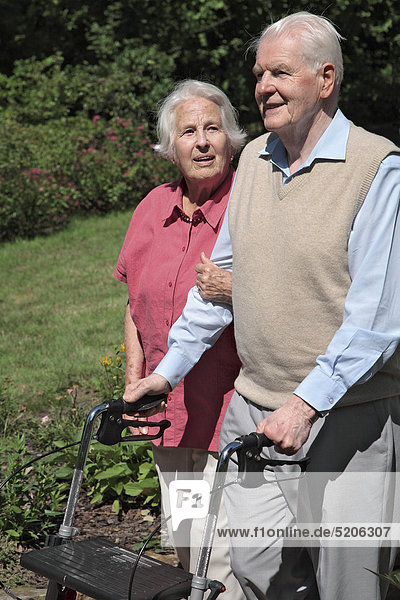 Seniorenpaar  gehen spazieren  er mit Gehwagen