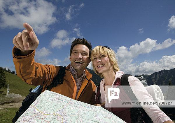 Paar beim Bergwandern  mit Landkarte  er zeigt auf etwas