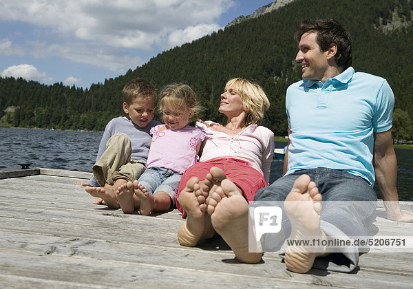 Familie  sitzen auf Steg an See