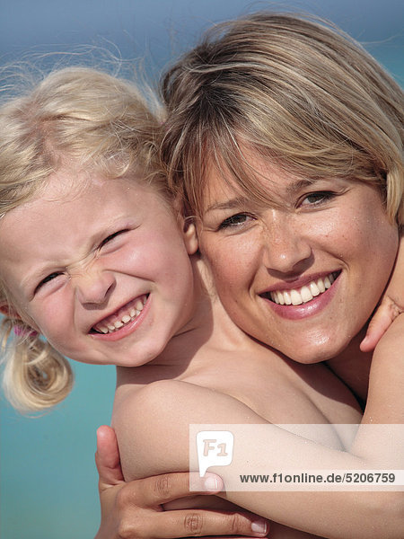 Mutter mit kleiner Tochter am Strand  umarmt  Porträt