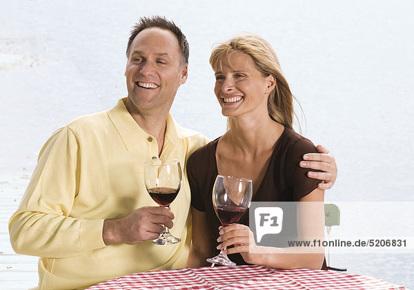 Paar  sitzen am Wasser  trinken Rotwein