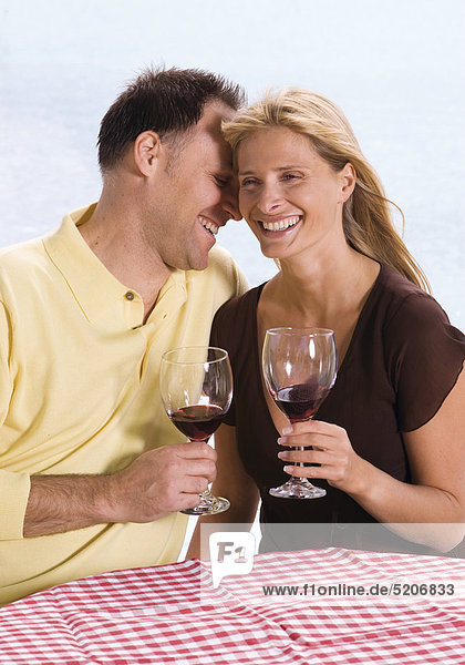 Paar  sitzen am Wasser  trinken Rotwein