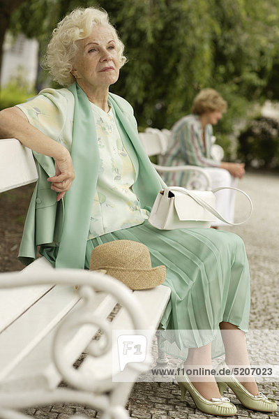 Seniorin sitzt auf Parkbank