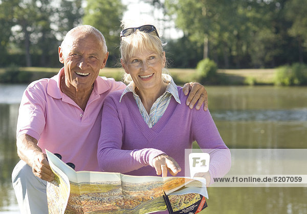 Seniorenpaar mit Landkarte an See