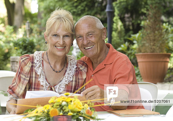 Seniorenpaar mit Speisekarte in Gartenrestaurant