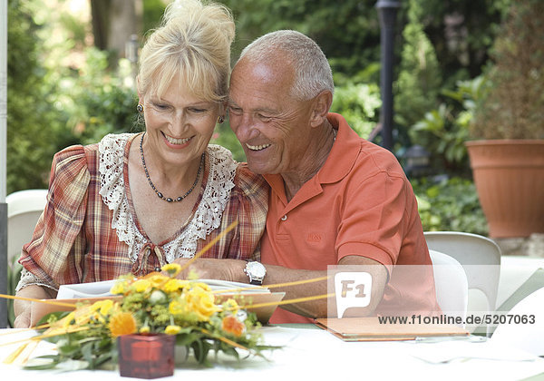 Seniorenpaar liest Speisekarte in Gartenrestaurant