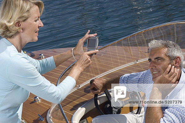 Seniorenpaar auf Motorboot  sie fotografiert ihn