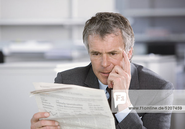 Mann liest im Büro Zeitung  angespannt