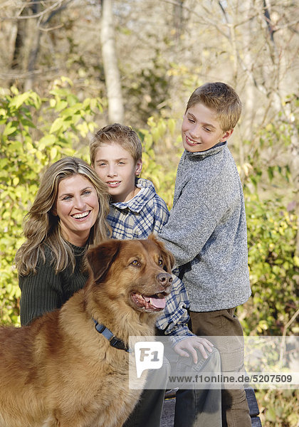 Mutter mit zwei Söhnen und Hund in herbstlichem Park