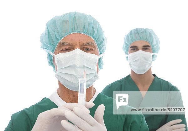 Älterer Chirurg mit Spritze  Kollege im Hintergrund