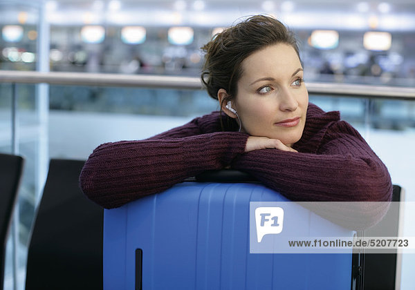 Frau wartet mit Koffer  hört Musik  Flughafen München
