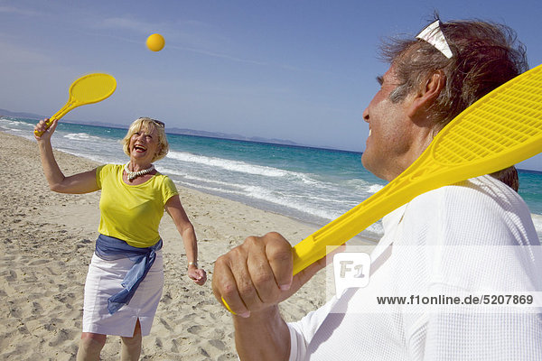 Älteres Paar spielt am Strand Softball