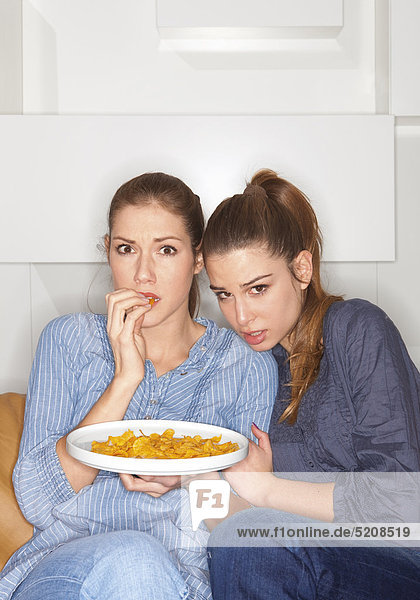 Zwei Frauen schauen ängstlich in den Fernseher
