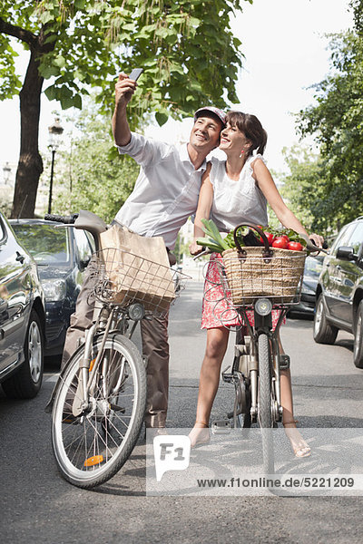 Couple riding bicycles and taking a picture of themselves with a mobile phone  Paris  Ile-de-France  France