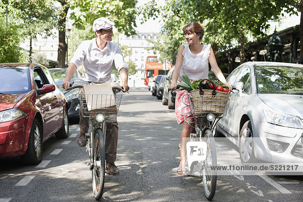 Couple carrying vegetables on bicycles  Paris  Ile-de-France  France