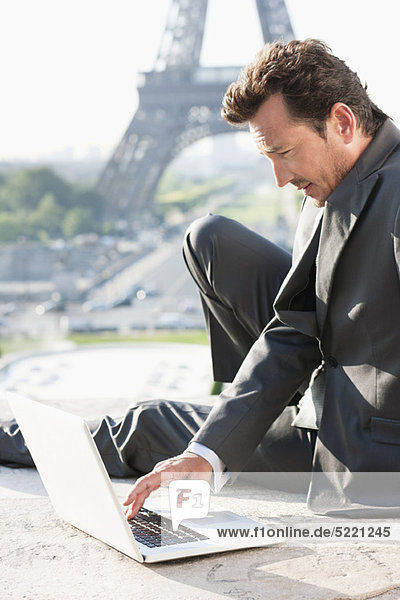 Businessman working on a laptop with the Eiffel Tower in the background  Paris  Ile-de-France  France