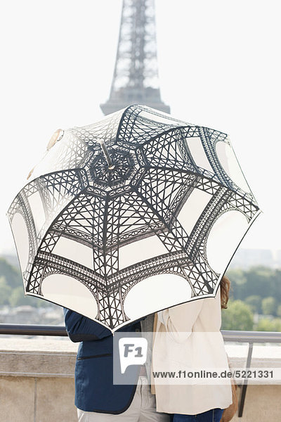 Paar unter einem Schirm mit dem Eiffelturm im Hintergrund  Paris  Ile-de-France  Frankreich