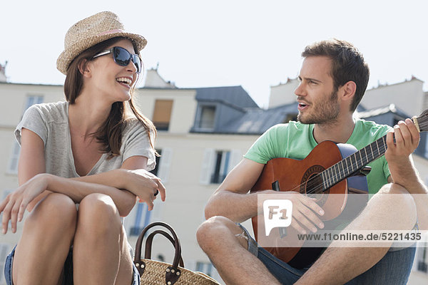 Mann spielt Gitarre mit einer lächelnden Frau  Canal St Martin  Paris  Ile-de-France  Frankreich