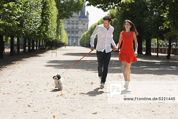 Couple running in a garden with a puppy  Terrasse De l'Orangerie  Jardin des Tuileries  Paris  Ile-de-France  France