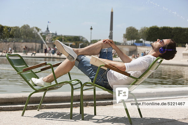 Mann auf einem Stuhl liegend und Musik hörend  Bassin achteckig  Jardin des Tuileries  Paris  Ile-de-France  Frankreich