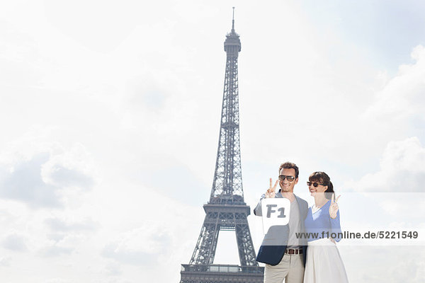 Paar mit Siegeszeichen mit dem Eiffelturm im Hintergrund  Paris  Ile-de-France  Frankreich