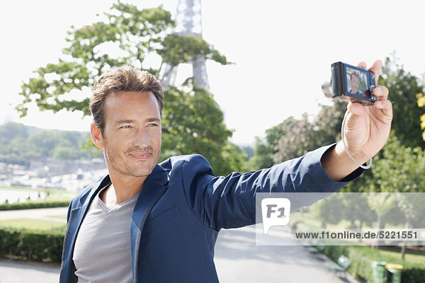 Man taking a picture of himself with a digital camera with the Eiffel Tower in the background  Paris  Ile-de-France  France