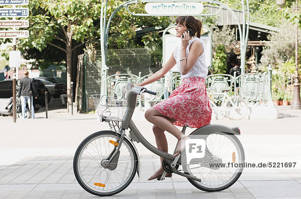 Frau auf dem Fahrrad und am Handy  Paris  Ile-de-France  Frankreich