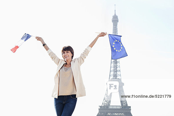 Frau mit einer Flagge der Europäischen Union und einer französischen Flagge mit dem Eiffelturm im Hintergrund  Paris  Ile-de-France  Frankreich