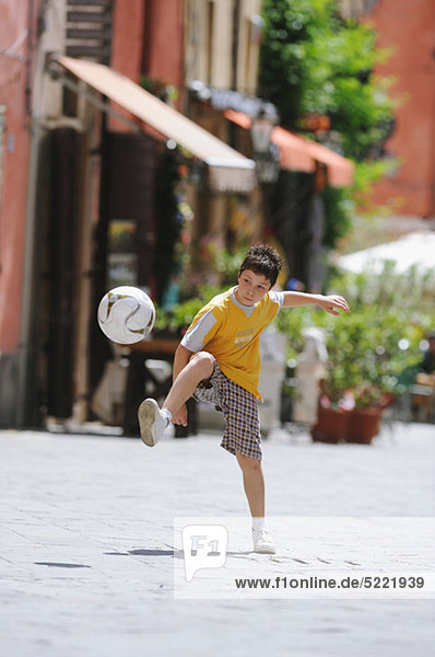 Junge spielen Fußball In Street