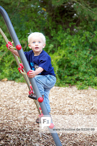 Kleiner blonder Junge auf einem Spielplatz