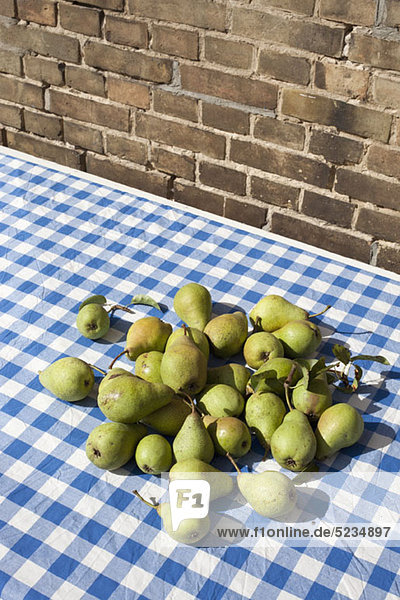 Ein Haufen frisch gepflückter Birnen auf einer karierten Tischdecke