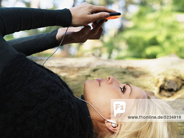 A woman wearing earphones and using a smart phone  outdoors