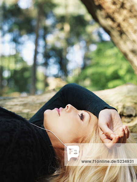 A woman lying outdoors wearing earphones  close-up  head and shoulders