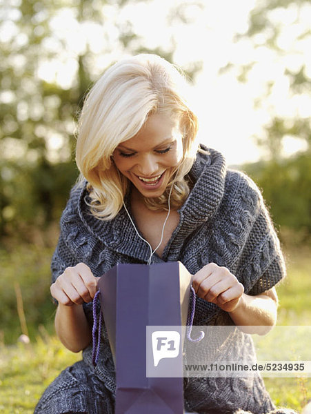 An excited woman looking into an open gift bag
