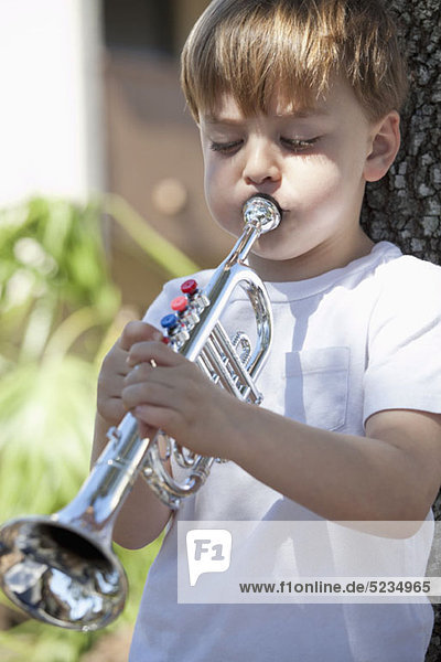 Ein Junge spielt eine Spielzeug-Trompete.