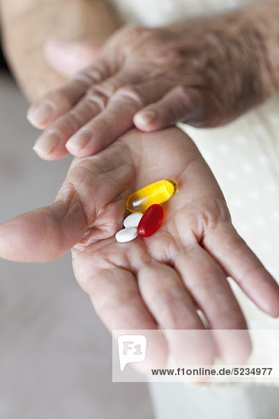 Detail von Kapseln und Tabletten in den Händen einer älteren Frau